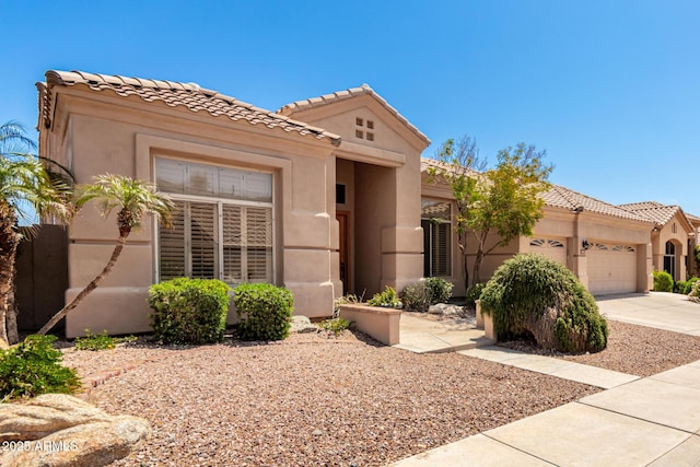 mediterranean / spanish-style home with a tiled roof, driveway, a garage, and stucco siding