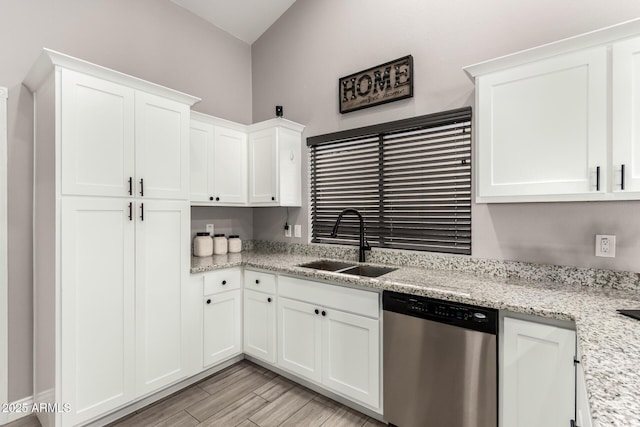 kitchen with light stone counters, wood tiled floor, white cabinets, a sink, and dishwasher