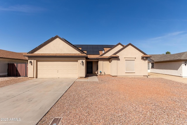 single story home featuring solar panels, stucco siding, concrete driveway, an attached garage, and fence