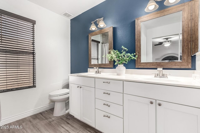 bathroom featuring toilet, double vanity, visible vents, and a sink