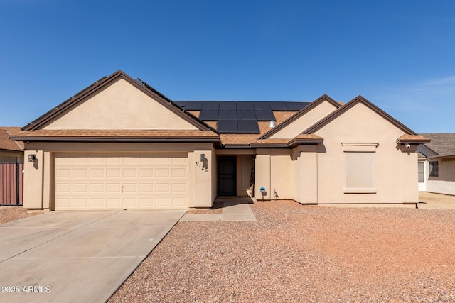 ranch-style house featuring a garage, concrete driveway, solar panels, and stucco siding