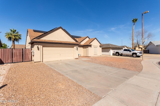 single story home with roof mounted solar panels, driveway, fence, and stucco siding