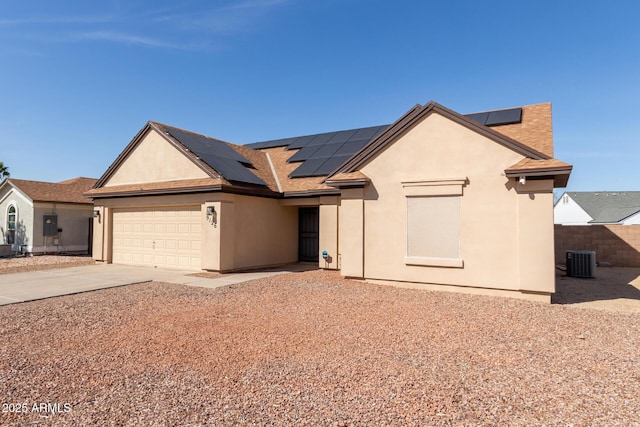 single story home featuring stucco siding, concrete driveway, roof mounted solar panels, central AC, and a garage