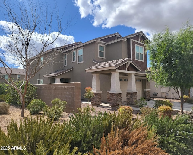 craftsman-style home featuring fence, stucco siding, a garage, stone siding, and driveway