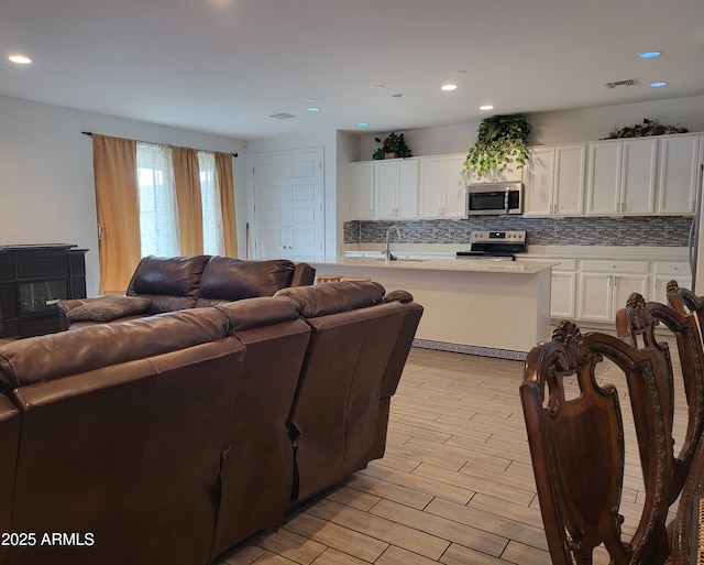 living room with recessed lighting, visible vents, and light wood-style floors