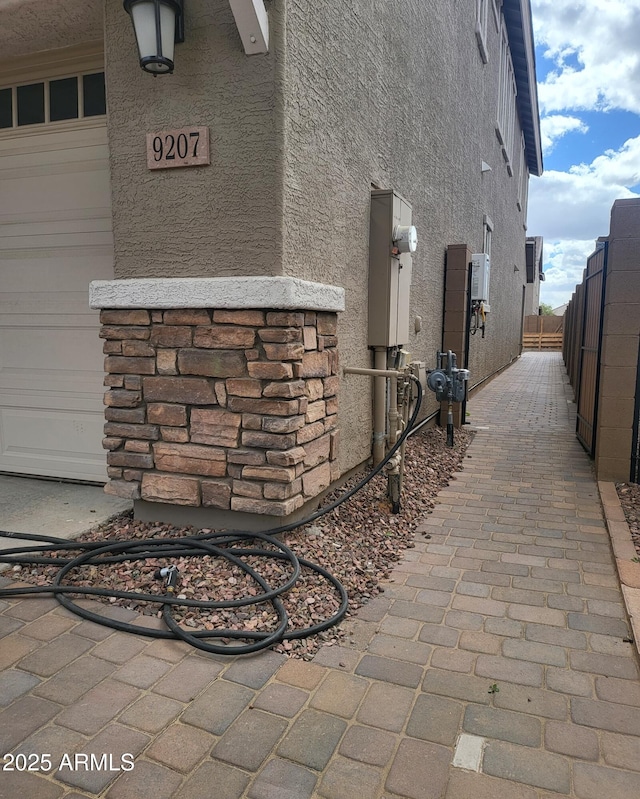 view of home's exterior with stucco siding, a garage, and fence