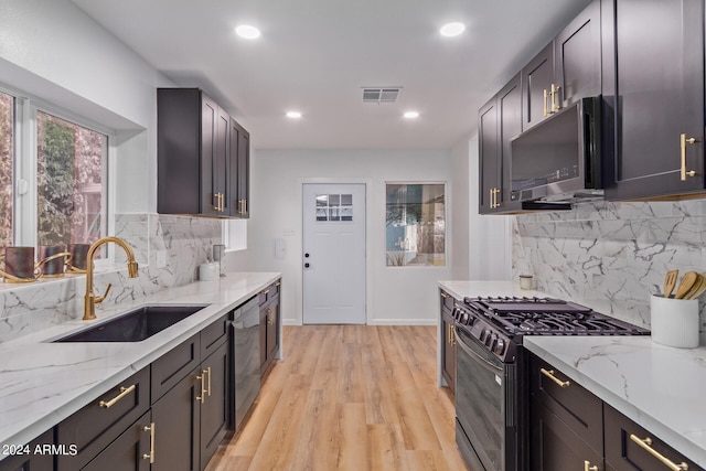 kitchen with appliances with stainless steel finishes, tasteful backsplash, sink, and light stone countertops