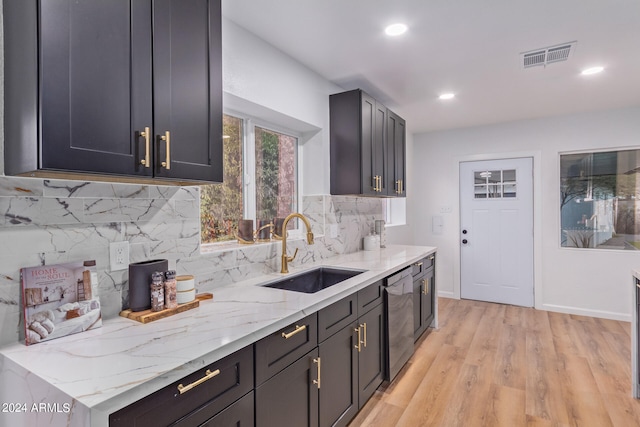 kitchen featuring light stone counters, light hardwood / wood-style floors, tasteful backsplash, and sink