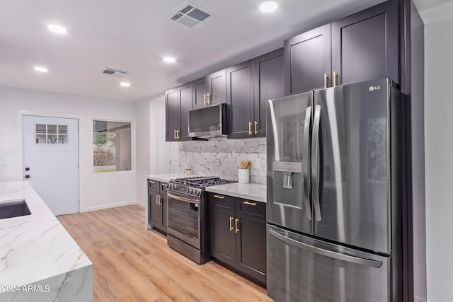 kitchen featuring light hardwood / wood-style flooring, light stone countertops, stainless steel appliances, sink, and decorative backsplash