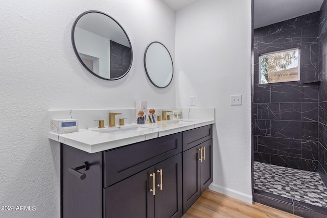 bathroom with tiled shower, vanity, and hardwood / wood-style flooring