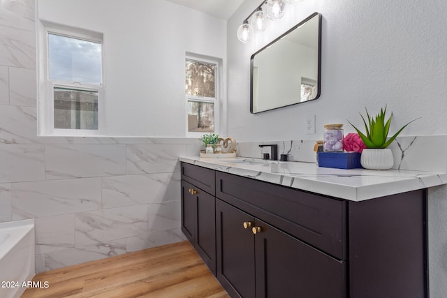 bathroom with vanity, tile walls, hardwood / wood-style flooring, and a washtub