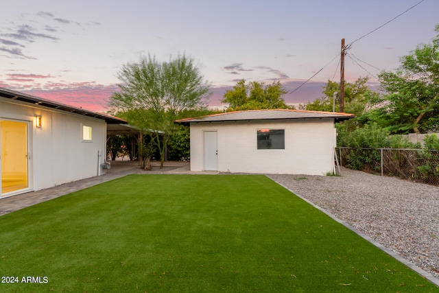 back house at dusk with a lawn