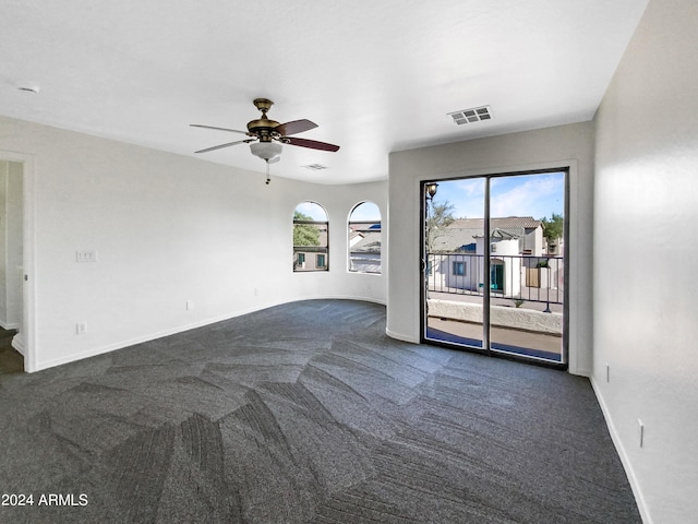 empty room featuring a wealth of natural light, visible vents, a ceiling fan, and baseboards