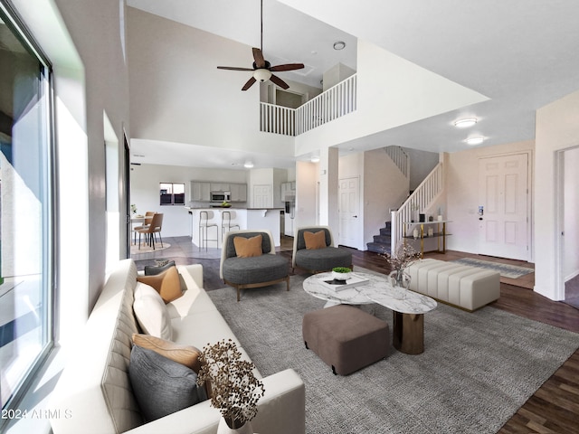 living room with a towering ceiling, wood-type flooring, and ceiling fan