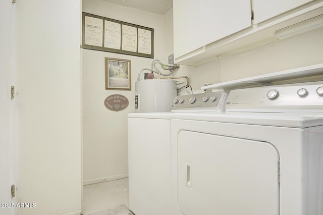 laundry room with water heater, washer and dryer, a textured ceiling, and cabinets