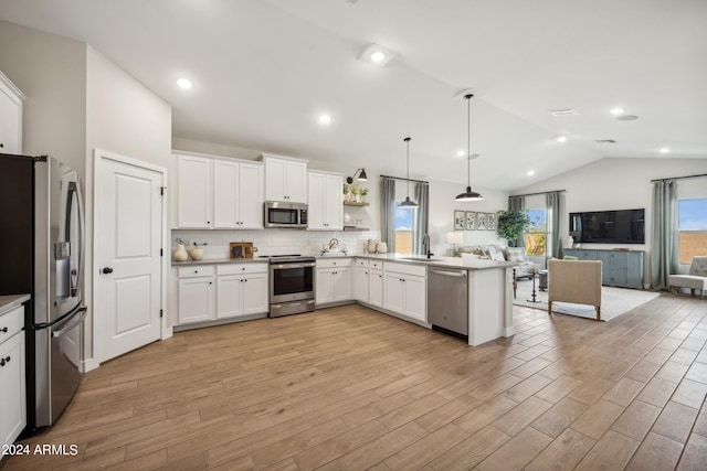 kitchen with decorative light fixtures, kitchen peninsula, appliances with stainless steel finishes, and light hardwood / wood-style flooring