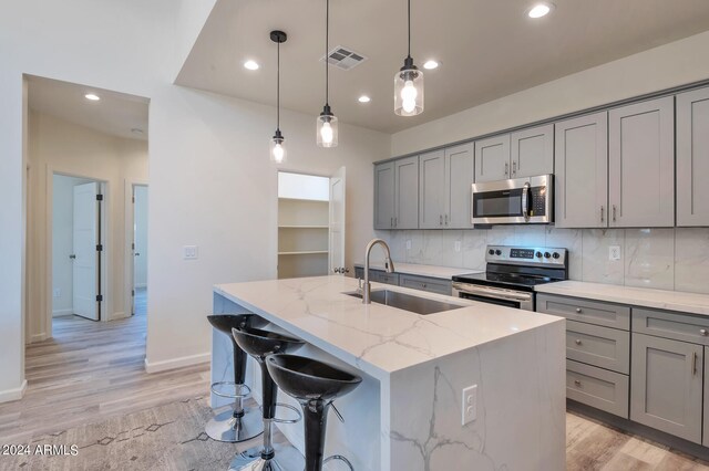 1278 W Calle Tuberia, Casa Grande, AZ 85194 - kitchen featuring decorative backsplash, light stone counters, stainless steel appliances, a kitchen island with sink, and sink
