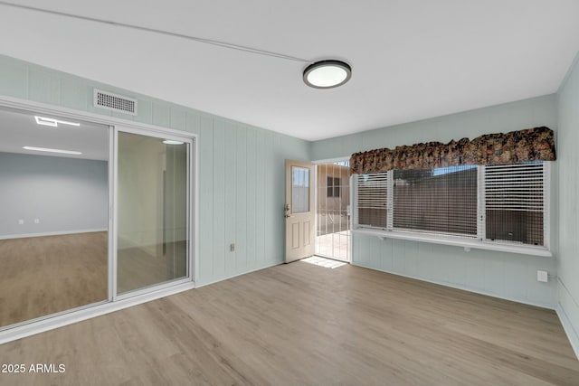 unfurnished living room featuring wood finished floors and visible vents