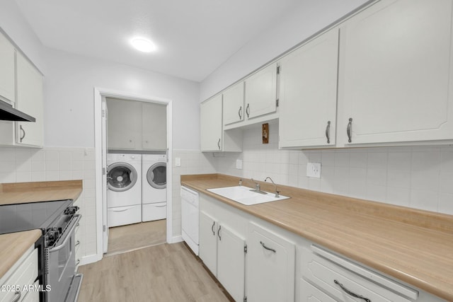 clothes washing area featuring light wood-type flooring, a sink, cabinet space, tile walls, and washing machine and clothes dryer