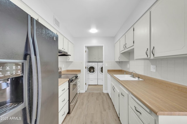 kitchen featuring under cabinet range hood, washing machine and dryer, electric stove, black fridge with ice dispenser, and a sink