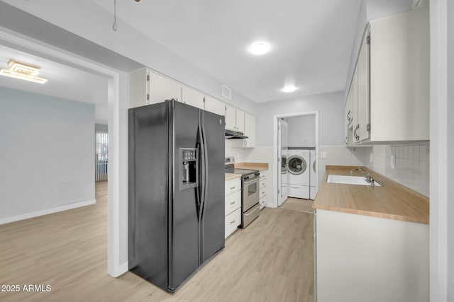 kitchen with washing machine and clothes dryer, under cabinet range hood, stainless steel electric range oven, black refrigerator with ice dispenser, and a sink