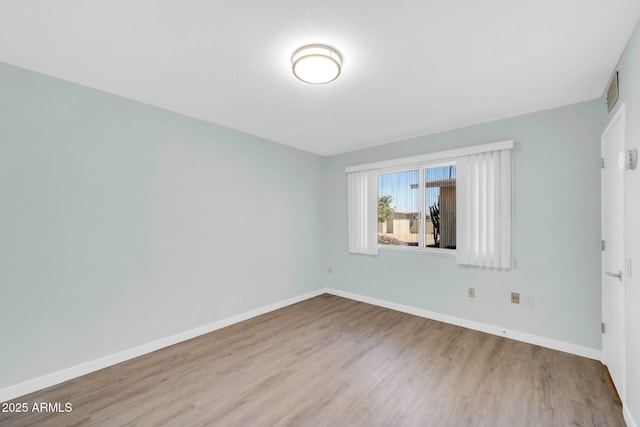 unfurnished room featuring visible vents, wood finished floors, and baseboards
