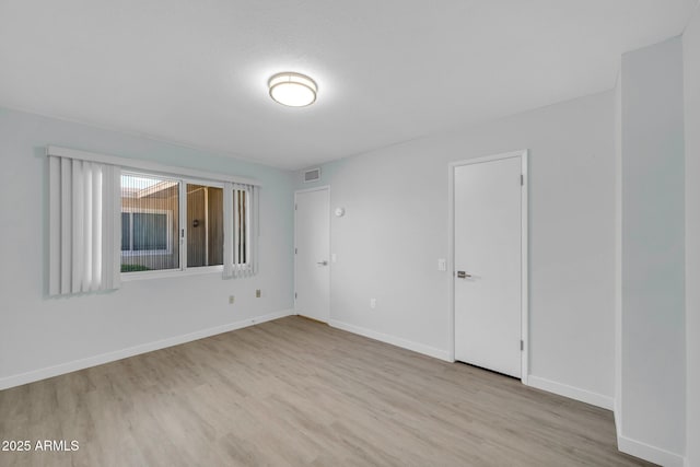 unfurnished room featuring visible vents, wood finished floors, and baseboards
