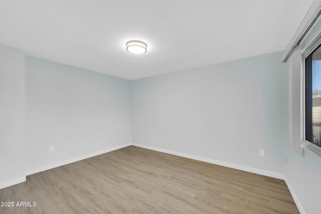 unfurnished room with baseboards and wood finished floors