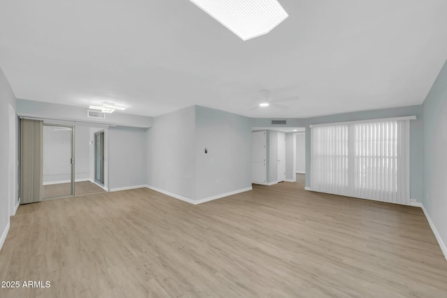 interior space featuring light wood-type flooring, visible vents, baseboards, and ceiling fan