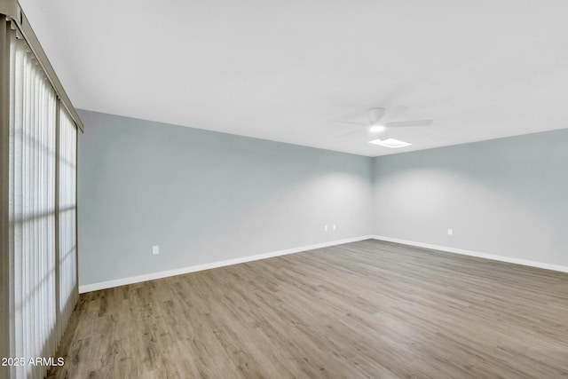 empty room featuring wood finished floors, baseboards, and ceiling fan