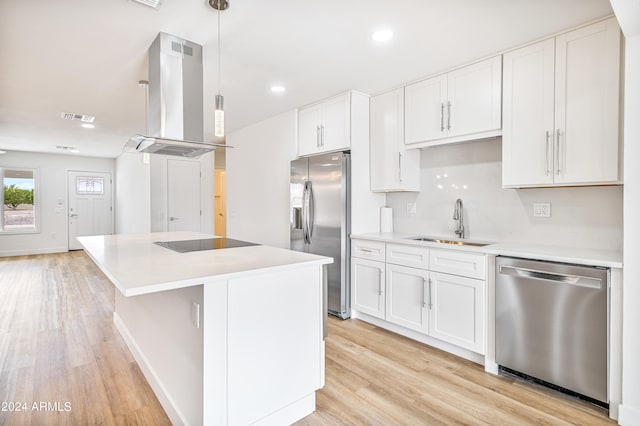 kitchen featuring sink, hanging light fixtures, island range hood, white cabinetry, and stainless steel appliances