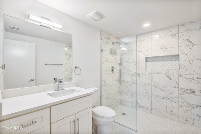 bathroom with a tile shower, vanity, and toilet