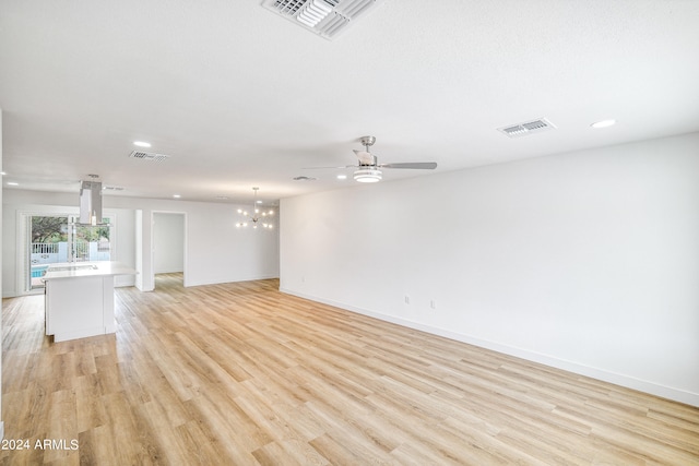 unfurnished living room featuring light hardwood / wood-style floors and ceiling fan with notable chandelier