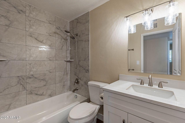 full bathroom with vanity, washtub / shower combination, toilet, and a textured wall