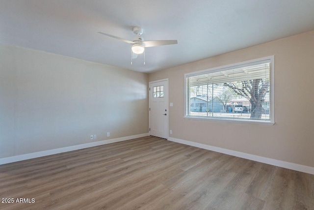 empty room with ceiling fan, baseboards, and wood finished floors