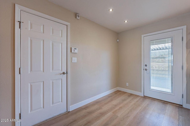 doorway with a wealth of natural light, baseboards, and light wood-style floors