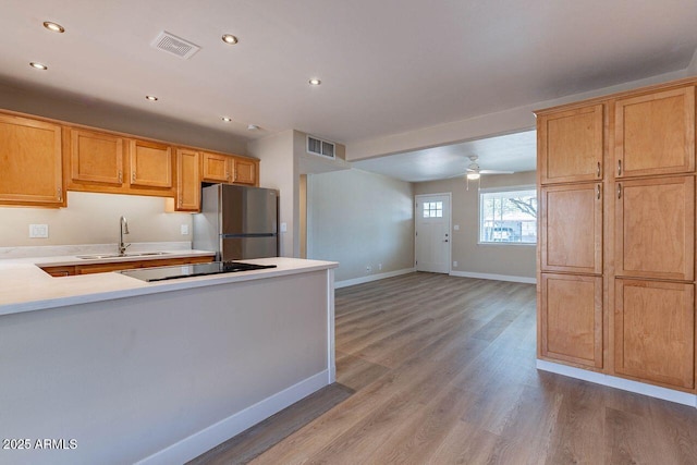 kitchen featuring light countertops, visible vents, freestanding refrigerator, and a sink