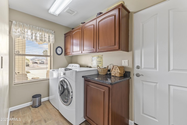 clothes washing area featuring cabinets, washing machine and dryer, and light hardwood / wood-style floors