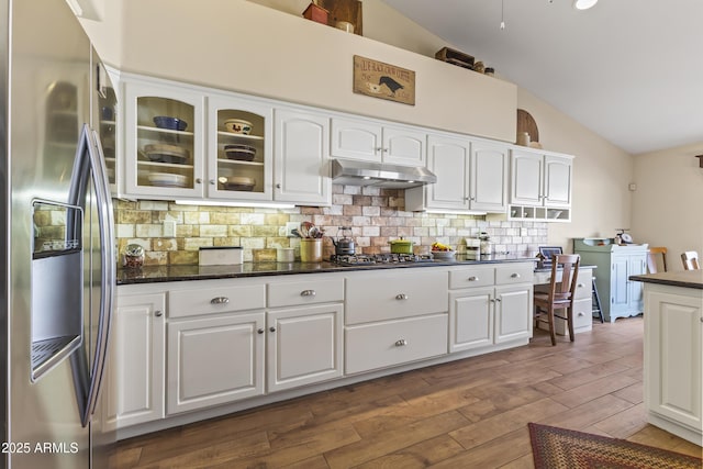 kitchen with backsplash, stainless steel appliances, white cabinets, dark hardwood / wood-style flooring, and vaulted ceiling