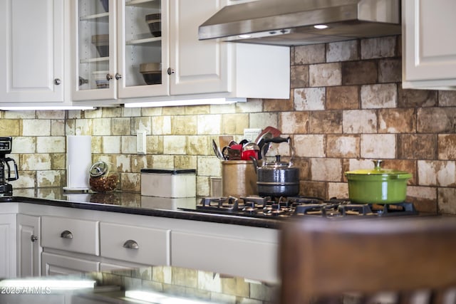 kitchen featuring ventilation hood, decorative backsplash, and white cabinets