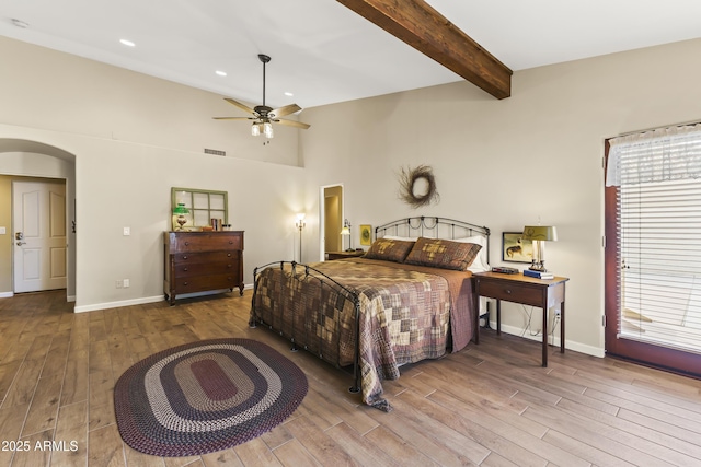 bedroom featuring ceiling fan, hardwood / wood-style flooring, beamed ceiling, and a high ceiling