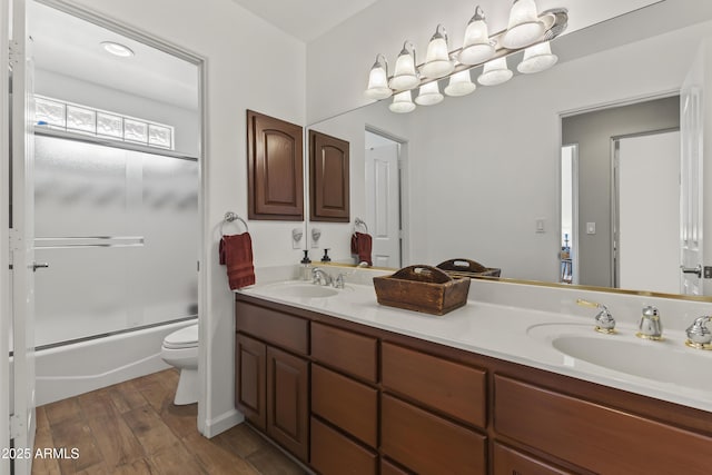 full bathroom featuring wood-type flooring, vanity, shower / bath combination with glass door, and toilet