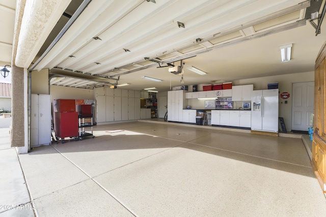 garage featuring a garage door opener and white refrigerator with ice dispenser