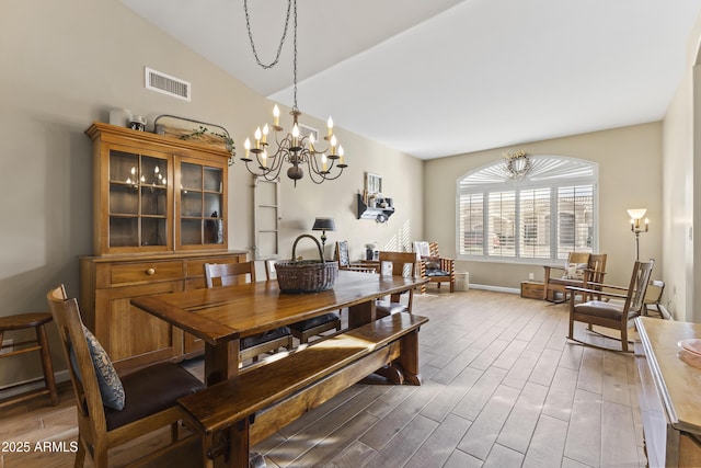 dining area with hardwood / wood-style flooring, a chandelier, and vaulted ceiling