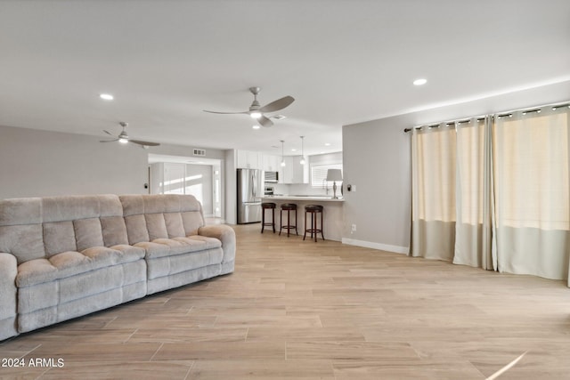 living room featuring visible vents, a ceiling fan, recessed lighting, light wood-style floors, and baseboards