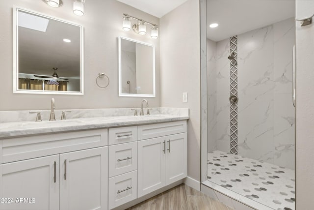 full bath with a sink, a marble finish shower, wood finished floors, and double vanity
