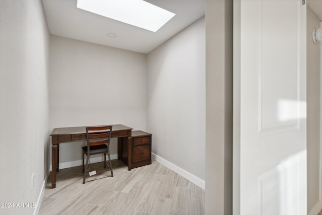 office with baseboards, a skylight, and light wood finished floors