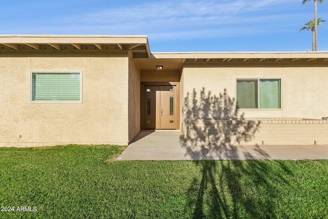 entrance to property with a lawn and stucco siding