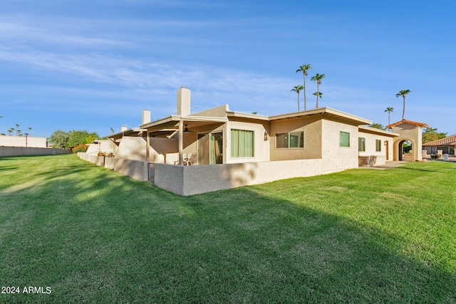 back of house with stucco siding and a lawn