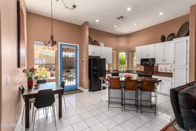 6531 E Star Valley St, Mesa, AZ 85215 - kitchen with a breakfast bar area, visible vents, white cabinets, black appliances, and dark countertops
